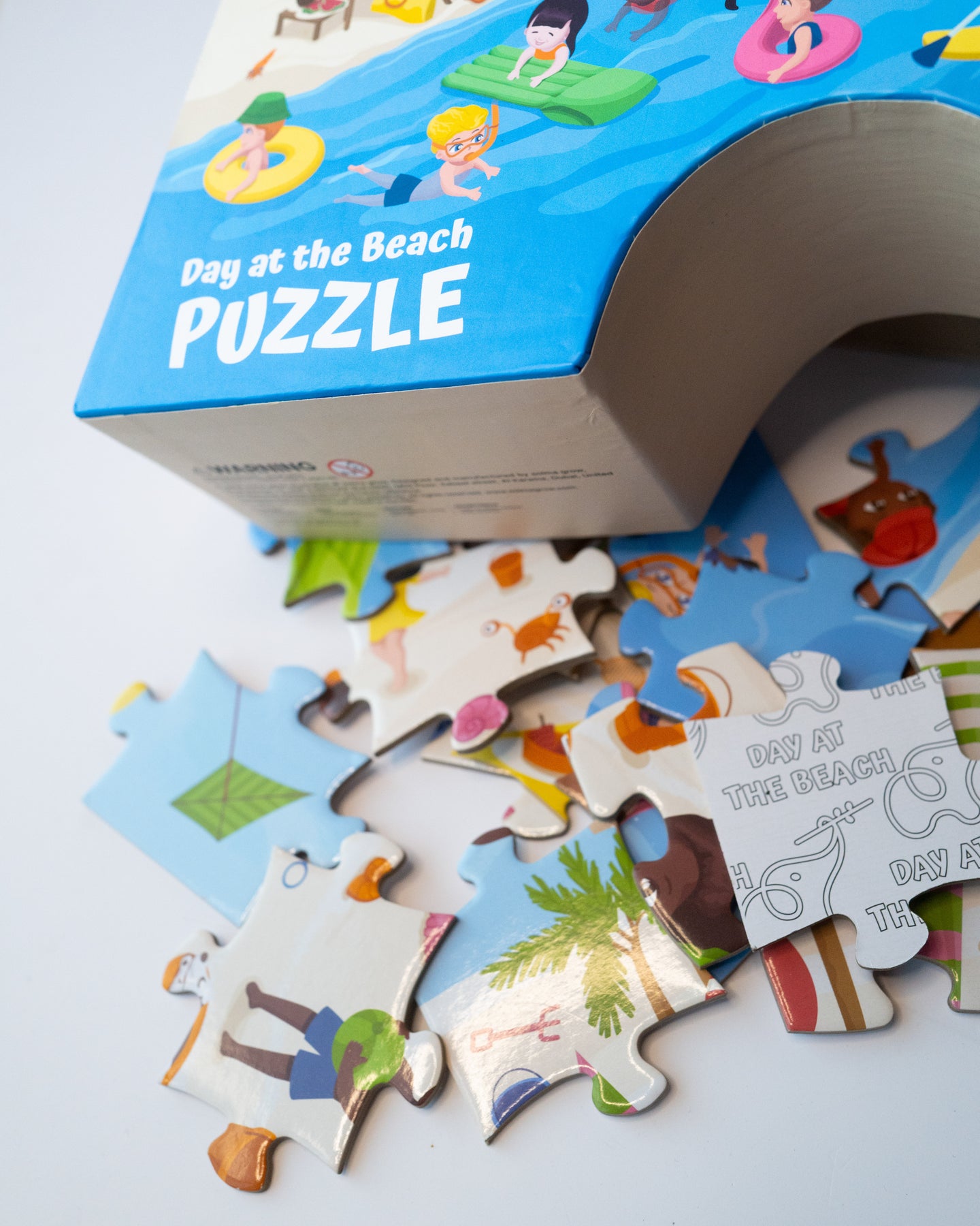 Zoomed-in sandcastle box and jigsaw puzzle pieces showing sea creatures, umbrellas, and kids playing on the beach